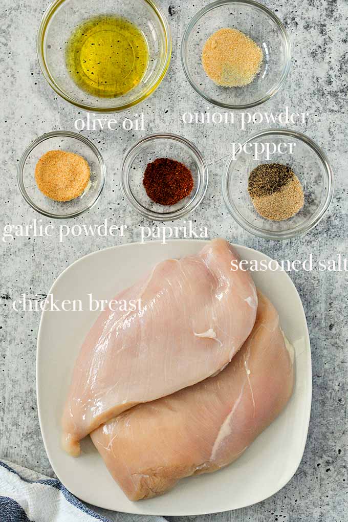 All of the ingredients needed to make air fryer chicken breast no breading like garlic powder, seasoned salt, olive oil, and chicken breast.