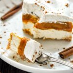 A square of no bake pumpkin pie cheesecake on a plate with a forkful of cake.