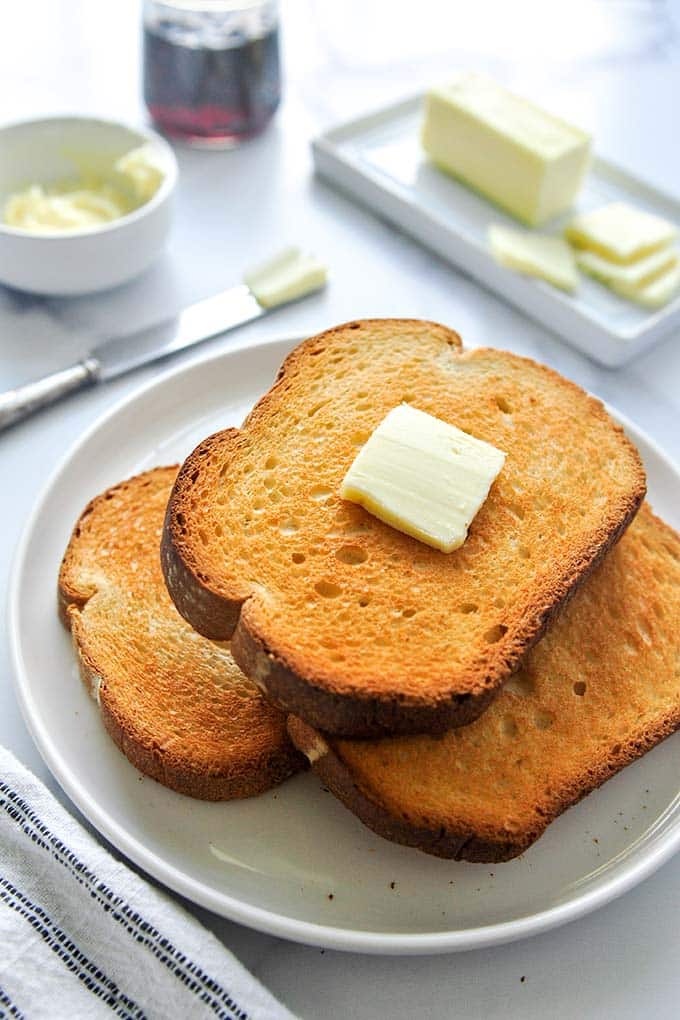 A stack of buttered toast on a plate.