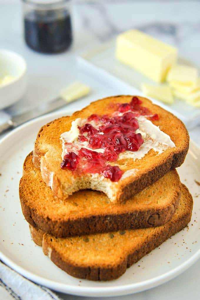 A stack of buttered and jellied toast on a plate for Air Fryer Toast.