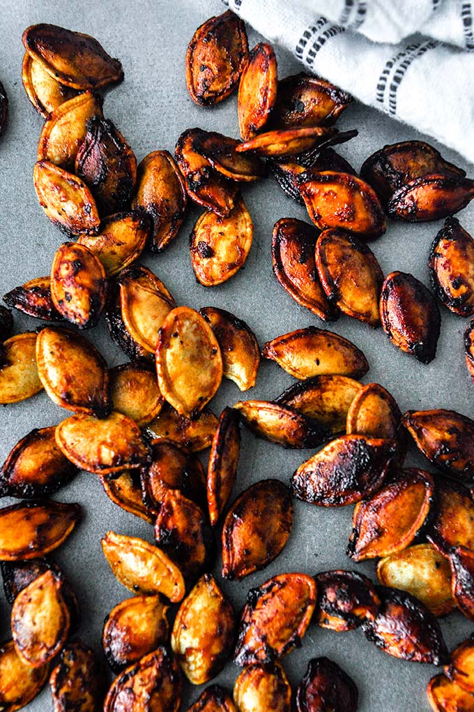 A tray of barbecue flavored air fryer pumpkin seeds with a white and black striped towel.