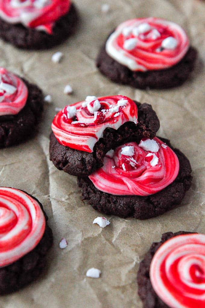 A peppermint brownie cookie that is leaned against another cookie with bites taken.