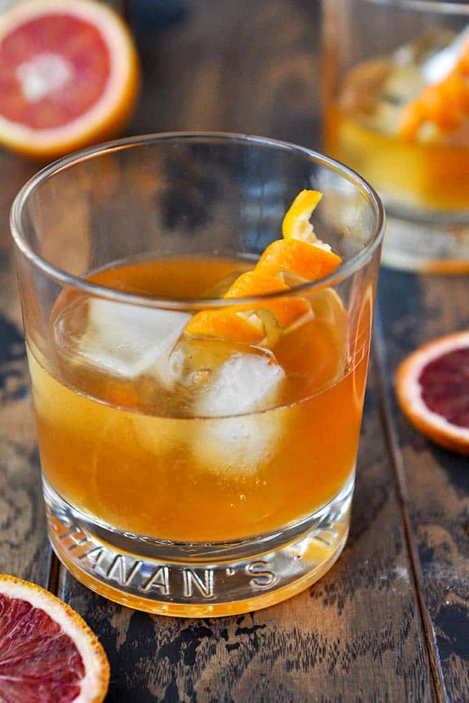 An old fashioned glass filled with blood orange old fashioned with an orange curl.