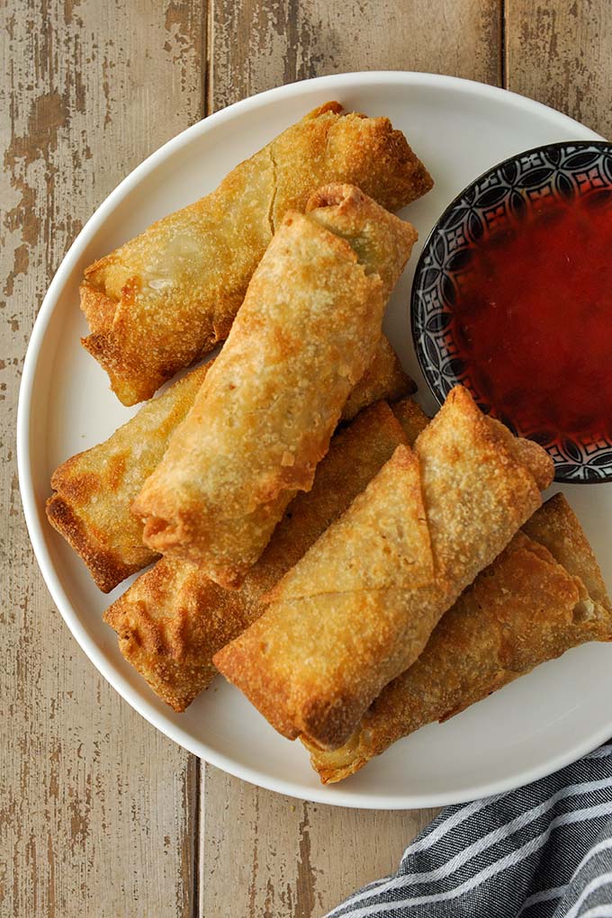 A plate of cooked frozen egg rolls in air fryer with sweet and sour sauce.