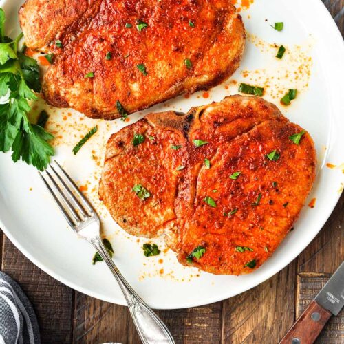 Best damn air fryer pork chops on a plate with a fork.