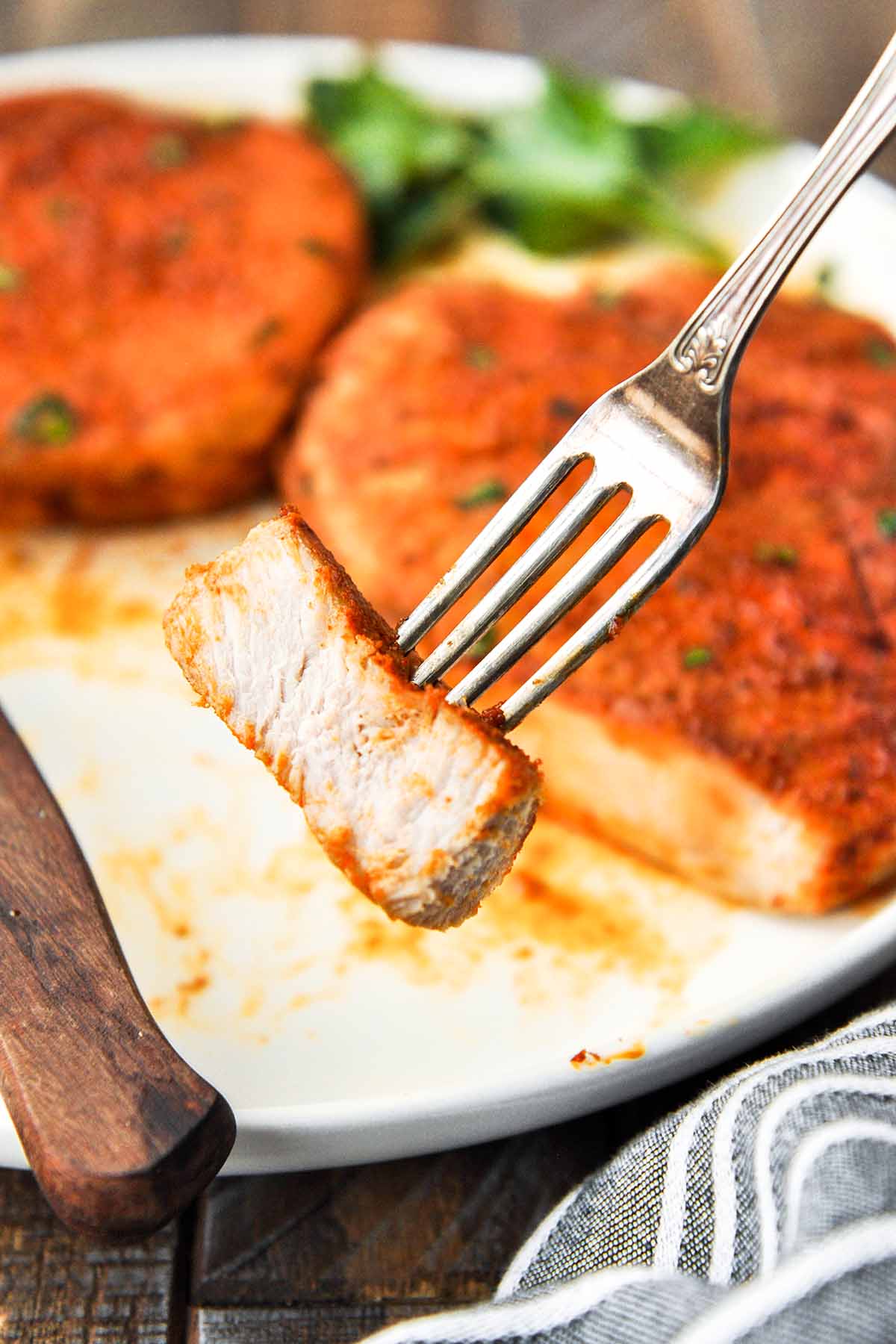 An up close of a bite of pork chop on a fork.