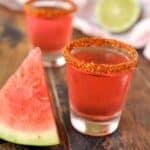 Two shot glasses of Mexican Candy Shot with a slice of watermelon.