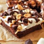 A close up of a rocky road brownie with more brownies in the background and marshmallows and chocolate chips in the foreground.