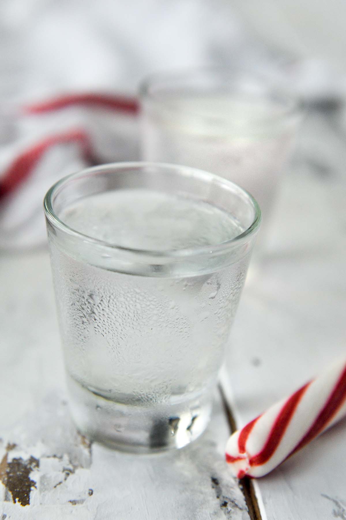 Two shot glasses of the polar bear shot with a peppermint stick.
