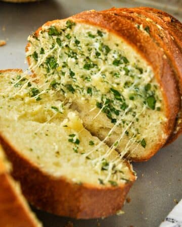 Gooey strings of cheese reach between two slices of garlic bread.