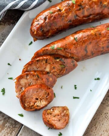 Chicken sausages on a plate with some sausage slices.