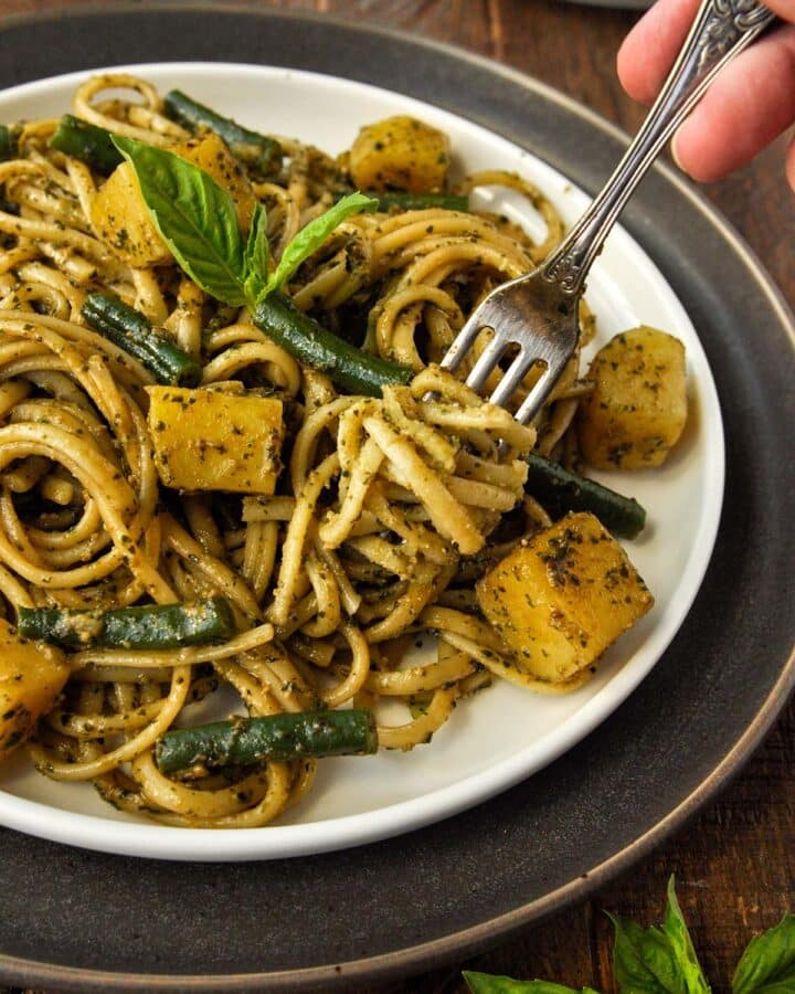 A plate trenette al pesto with a fork twirled around the pasta.