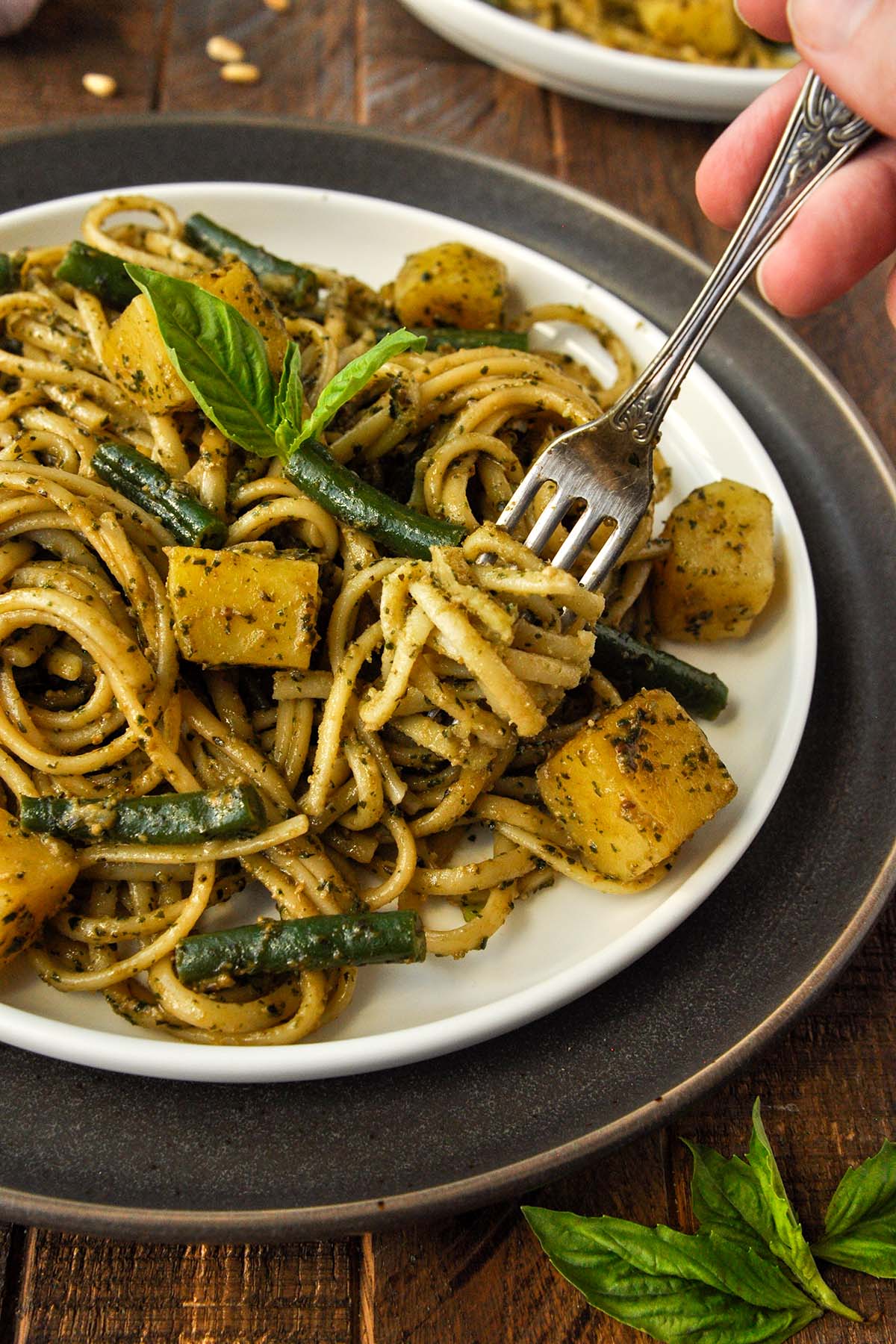 A plate trenette al pesto with a fork twirled around the pasta.