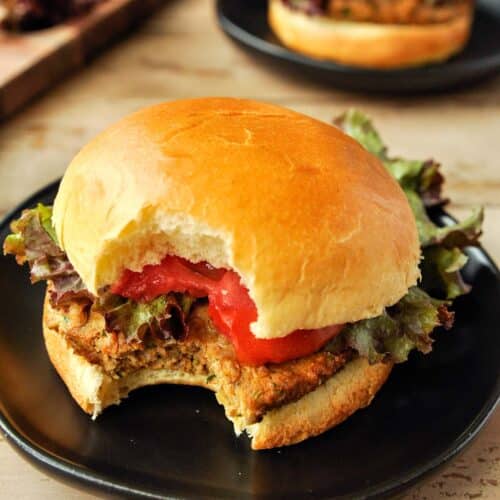 An air fryer turkey burger on a plate with a bite missing and a burger in the background.