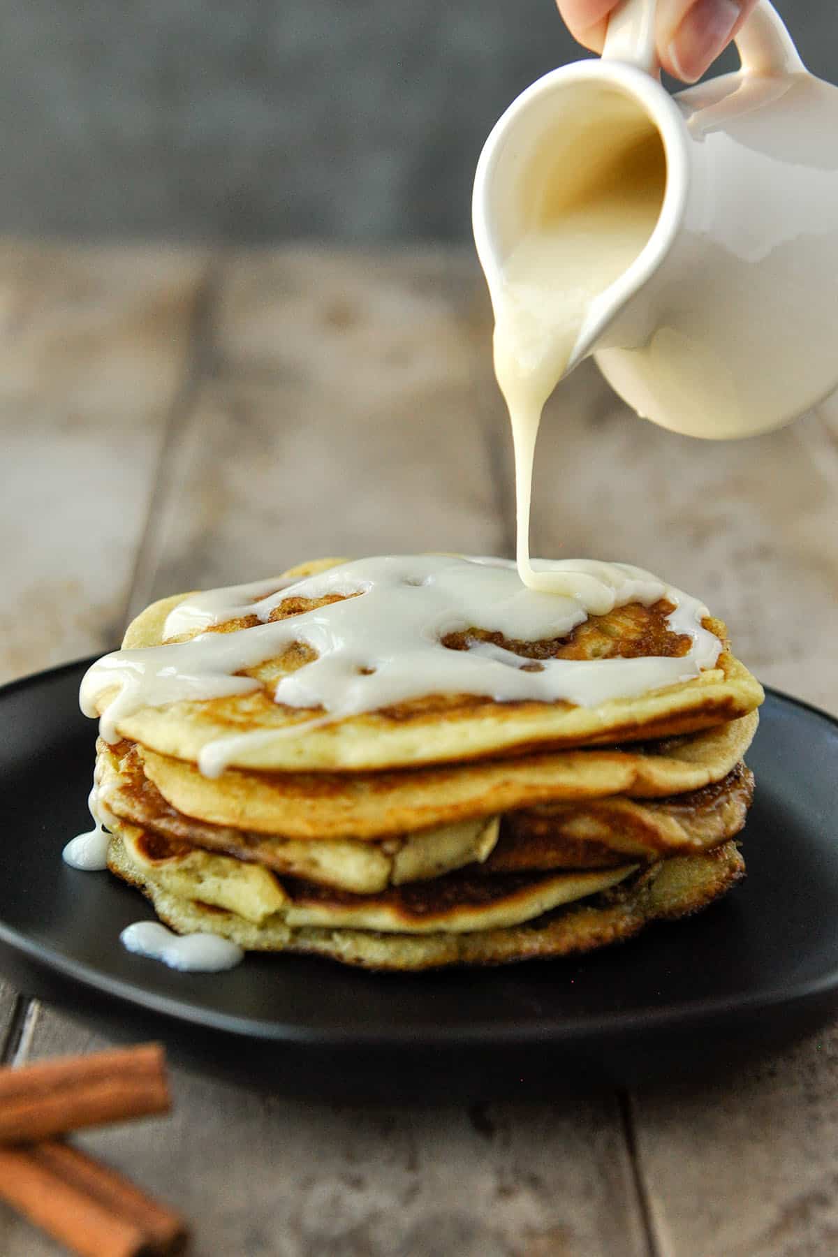 A stack of pancakes being drizzled with frosting.