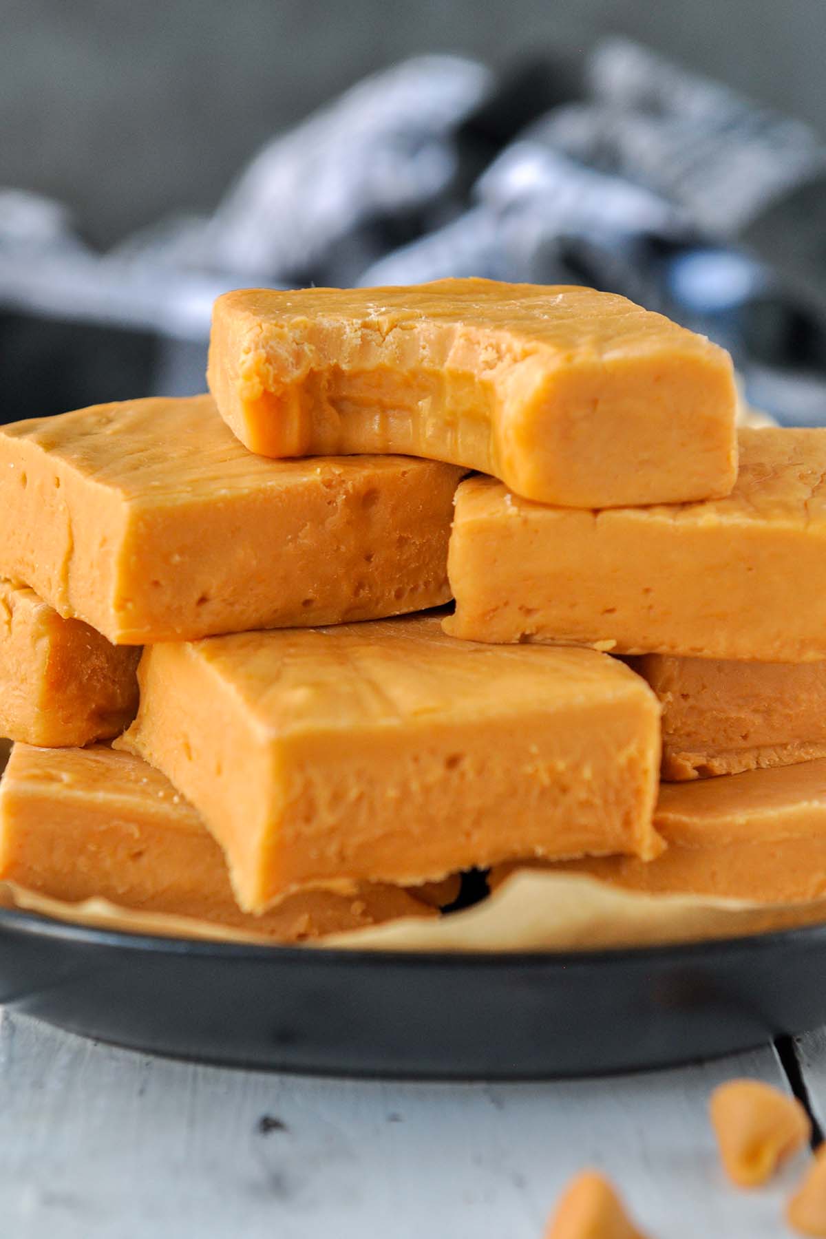 A plate of stacked butterscotch fudge, with the top piece missing a bite.