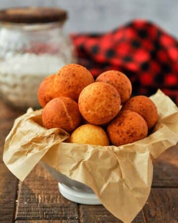 A bowl of buñuelos with a black and red towel.