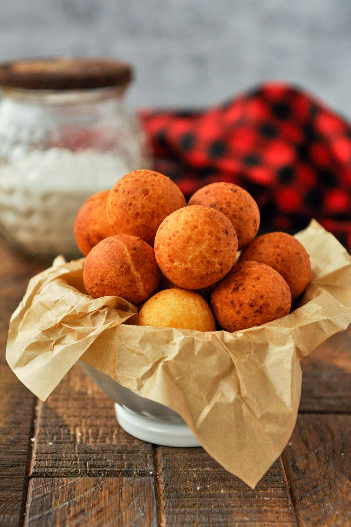 A bowl of buñuelos with a black and red towel.