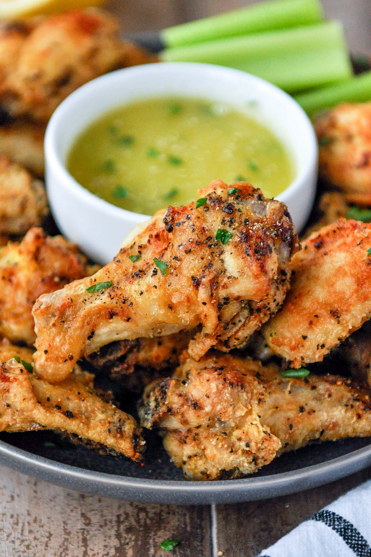 Close up of lemon pepper wings on a plate with lemon garlic sauce.