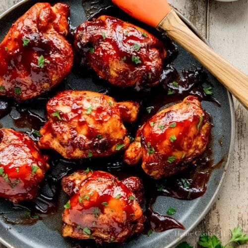 Above view of air fried barbecue chicken on a plate with a basting brush and a bowl of sauce.