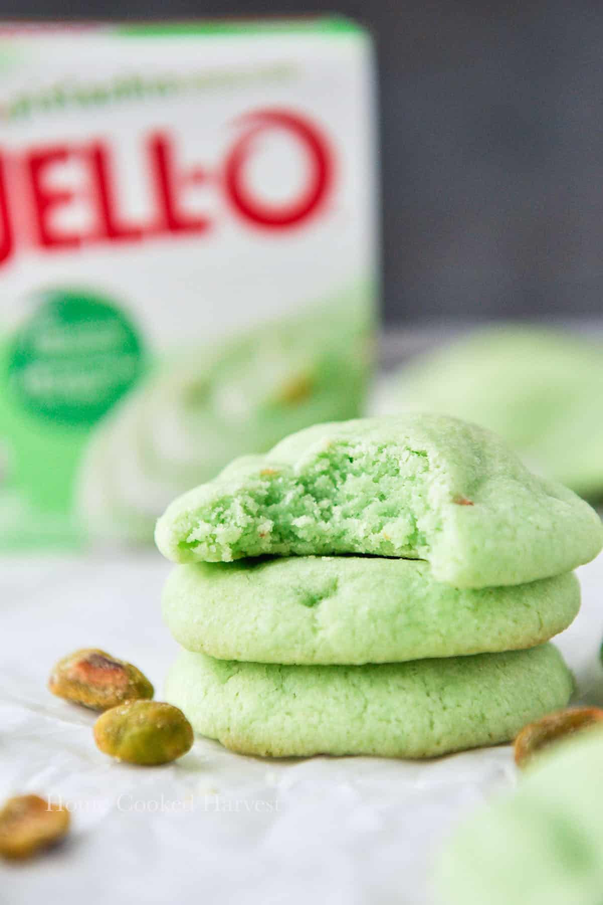 A small stack of cookies with the top one missing a bite and a box of jello pudding in the background.
