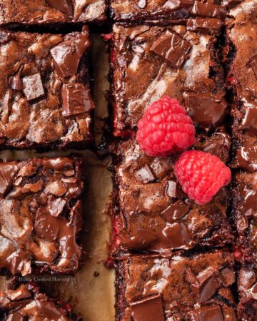 Above view of cut raspberry brownies with two raspberries.