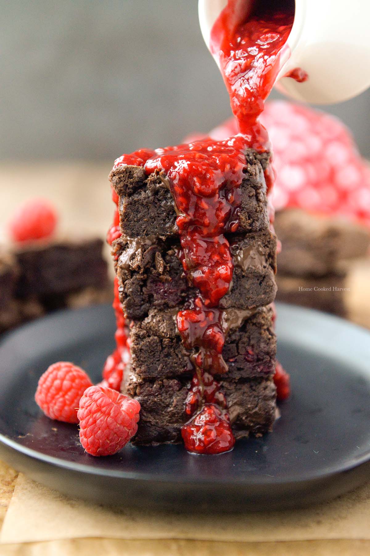 A stack of 4 brownies with raspberry sauce.
