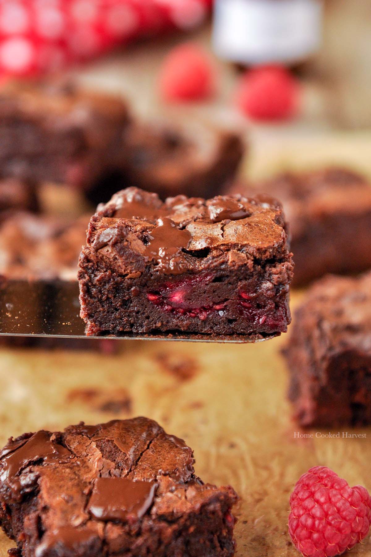 A raspberry brownie on a spatula with more brownies around.