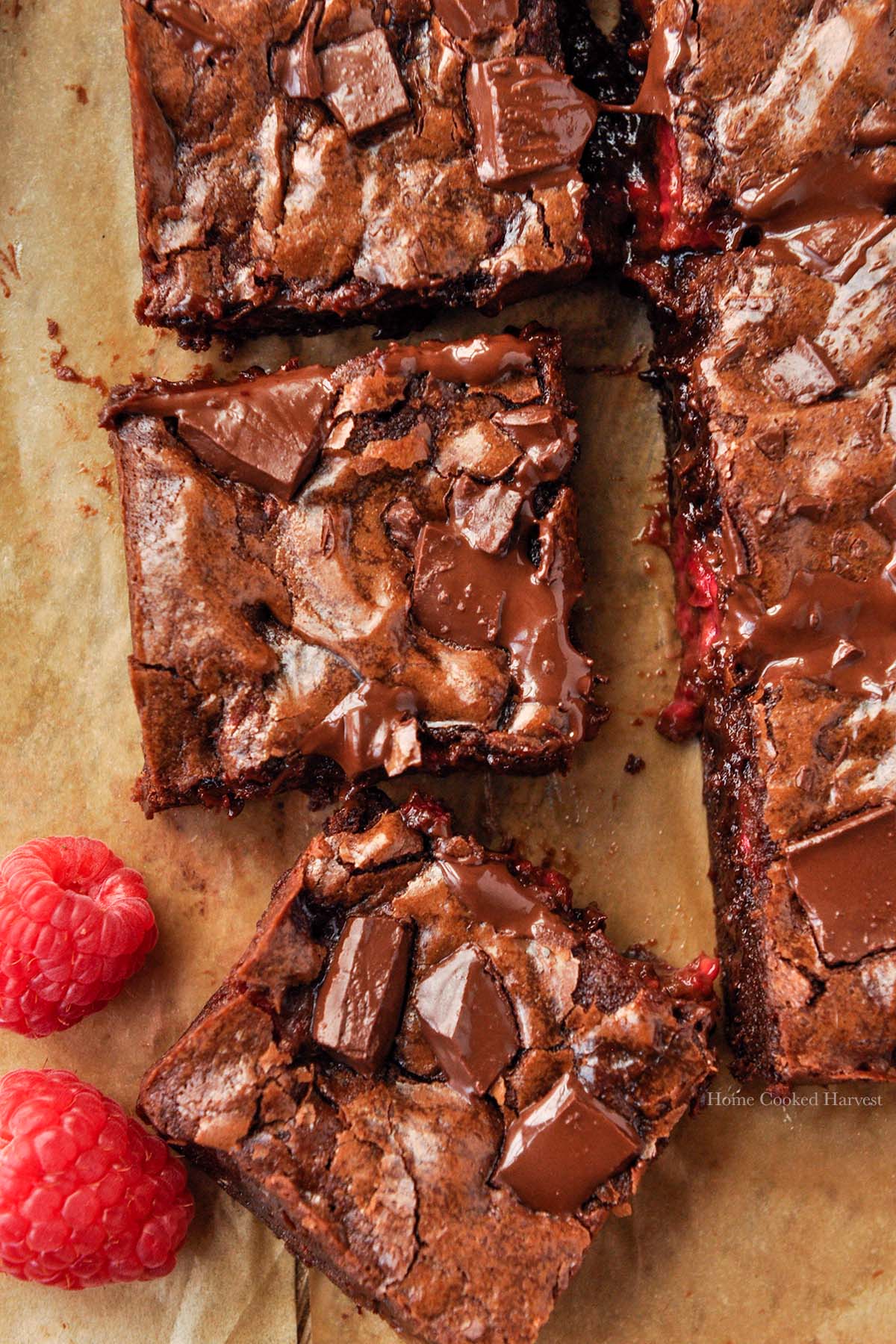 Above view of cut raspberry brownies with two raspberries.