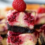 A stack of two raspberry bars with a raspberry on top.
