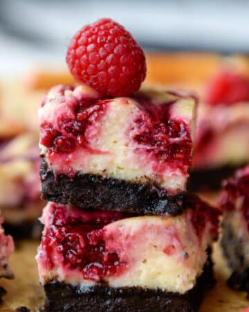 A stack of two raspberry bars with a raspberry on top.