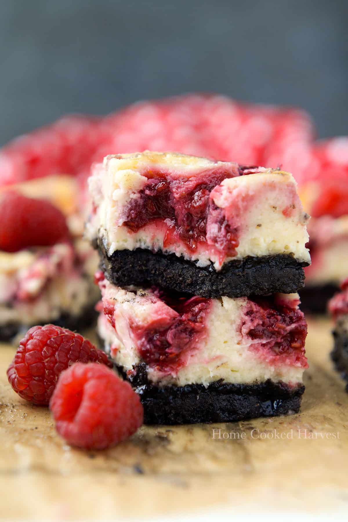 Two raspberry cheesecake squares stacked, a bite is missing from the top one. 