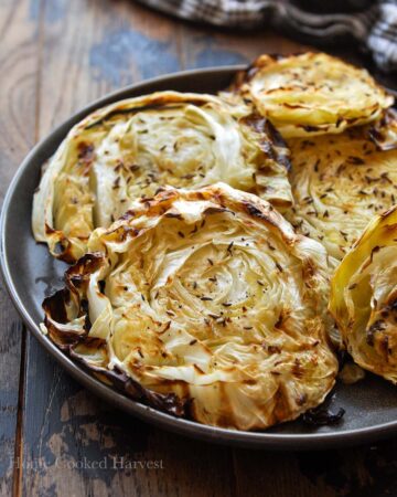 A plateful of cabbage steaks on a plate with a black and white towel.