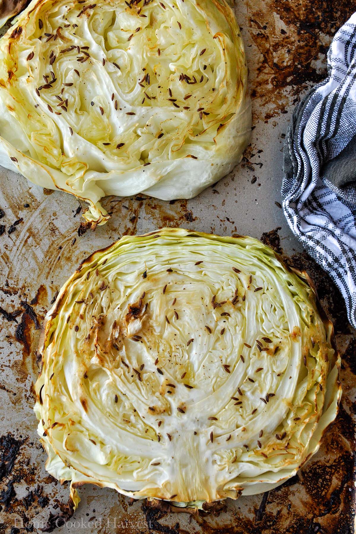 Above view of two thick cabbage steaks on a baking pan.