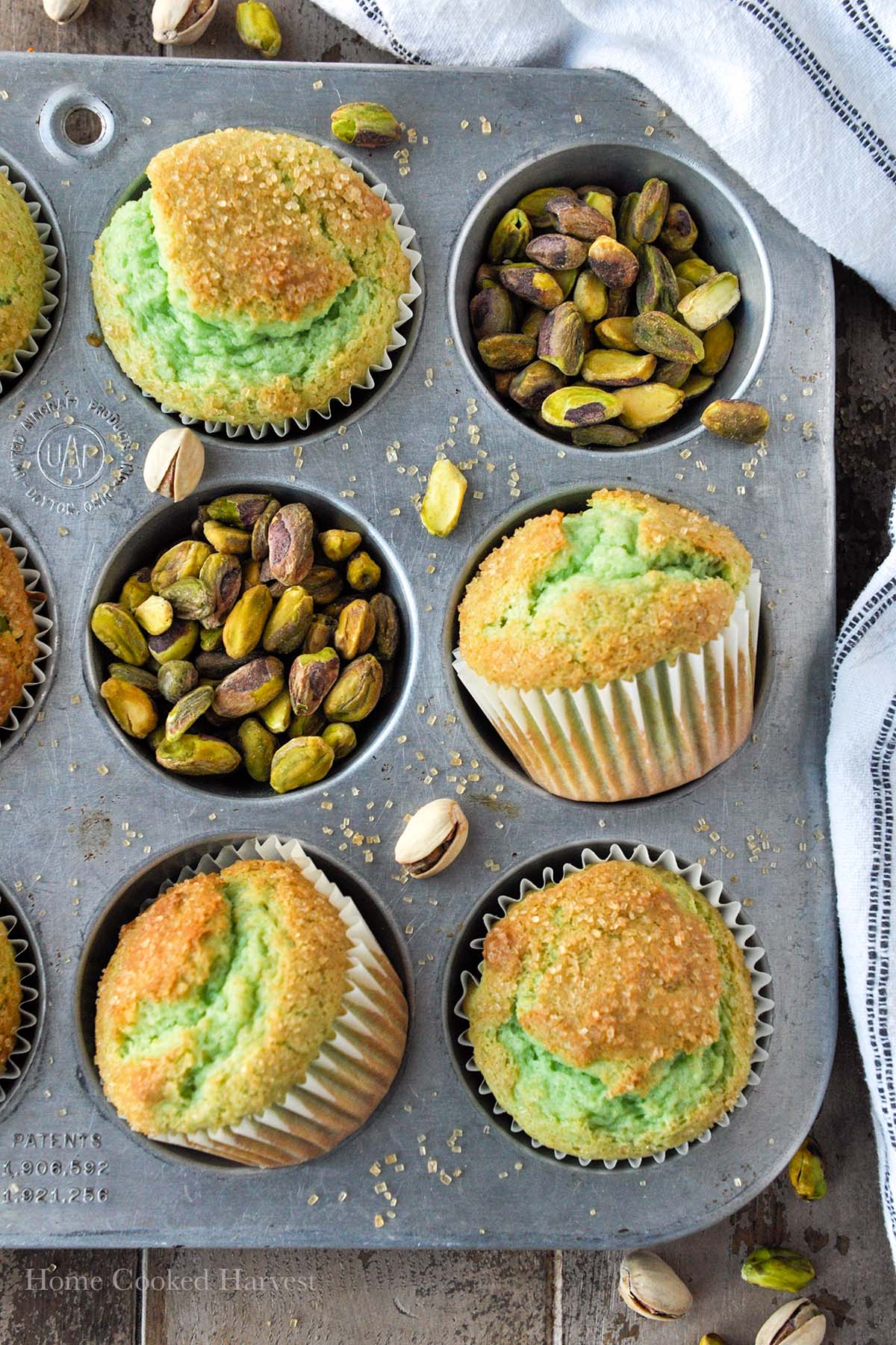 Above view of a muffin tin with pistachio muffins and pistachios.