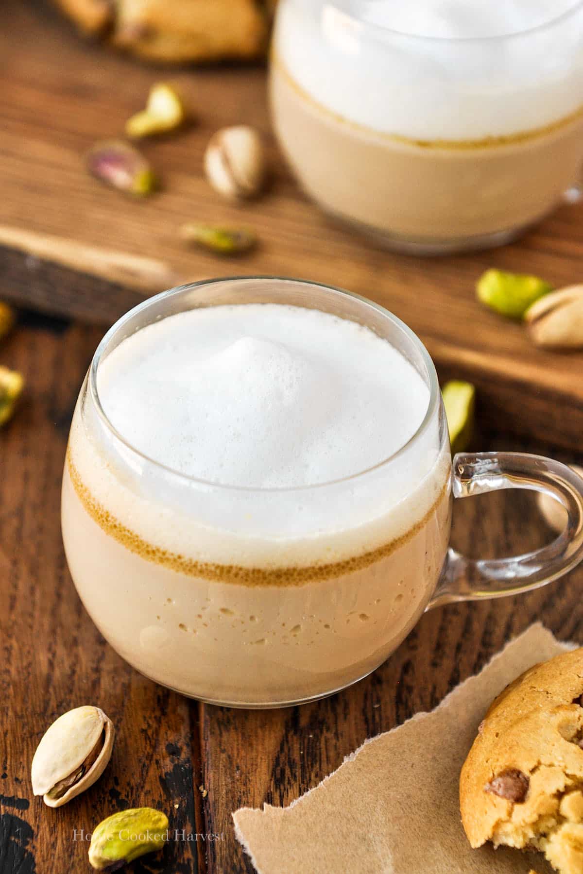 A mug of pistachio latte with another latte in the background.