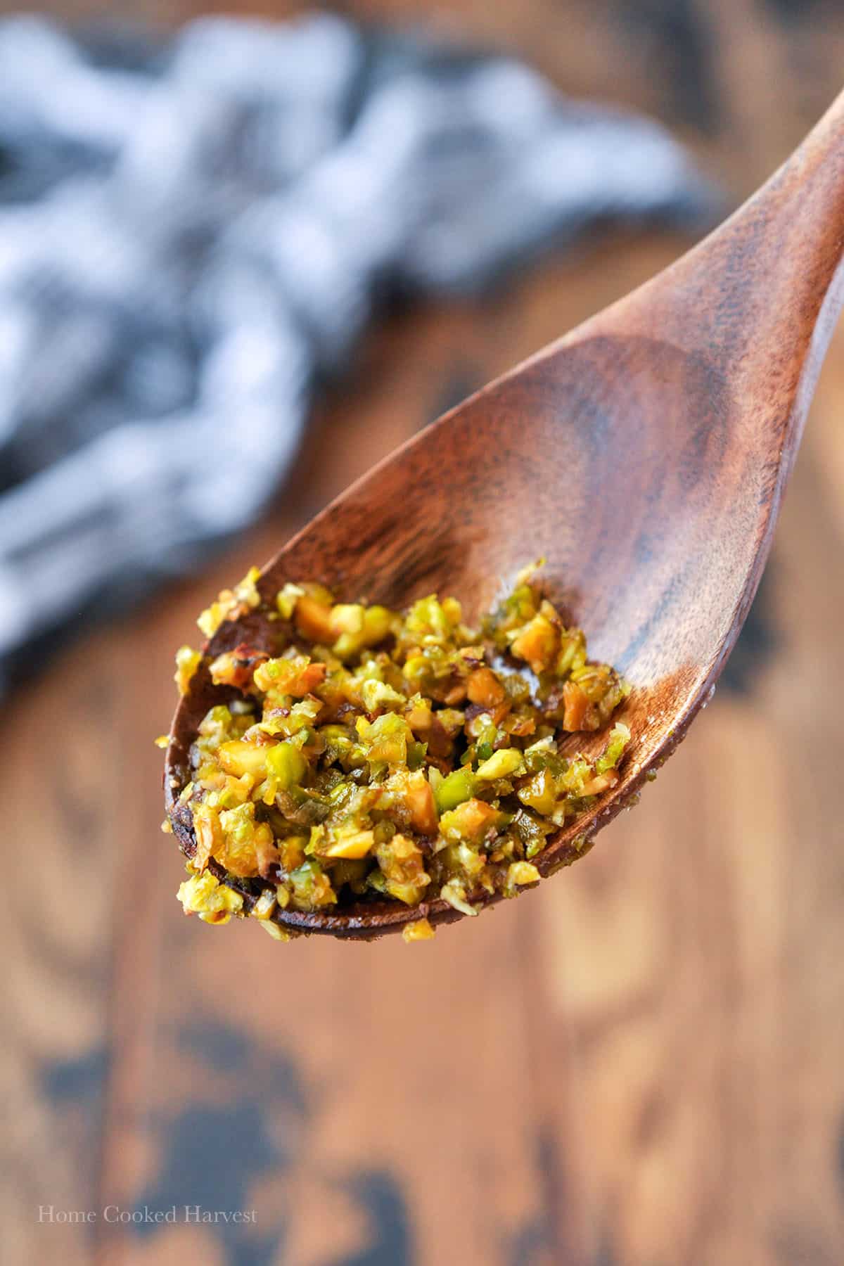 Close up of the strained chopped up pistachios on a wooden spoon.