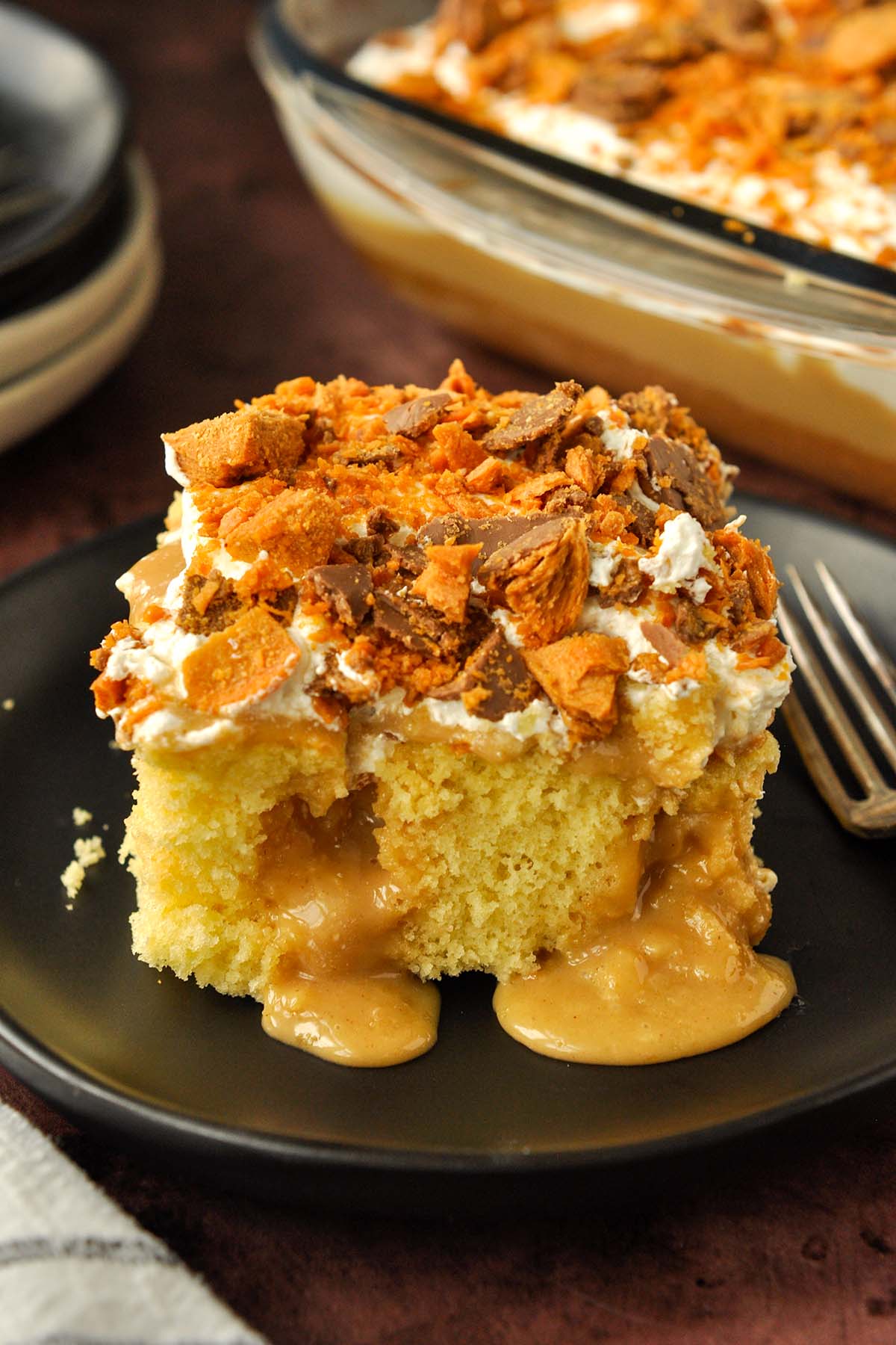 A big piece of butterfinger cake with peanut butter filling spilling out on a plate with a fork. 