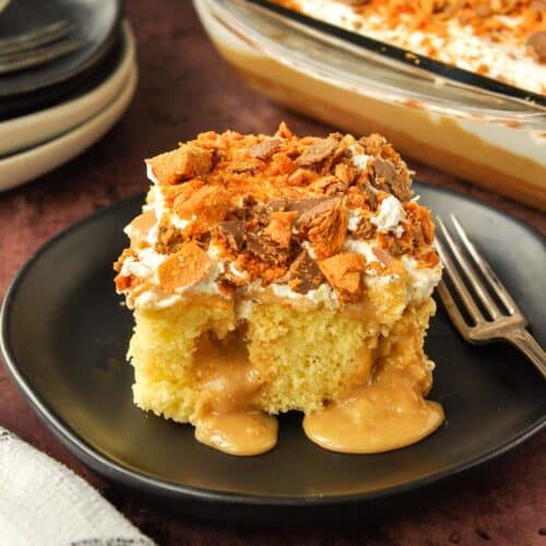 A big piece of butterfinger cake with peanut butter filling spilling out on a plate with a fork.