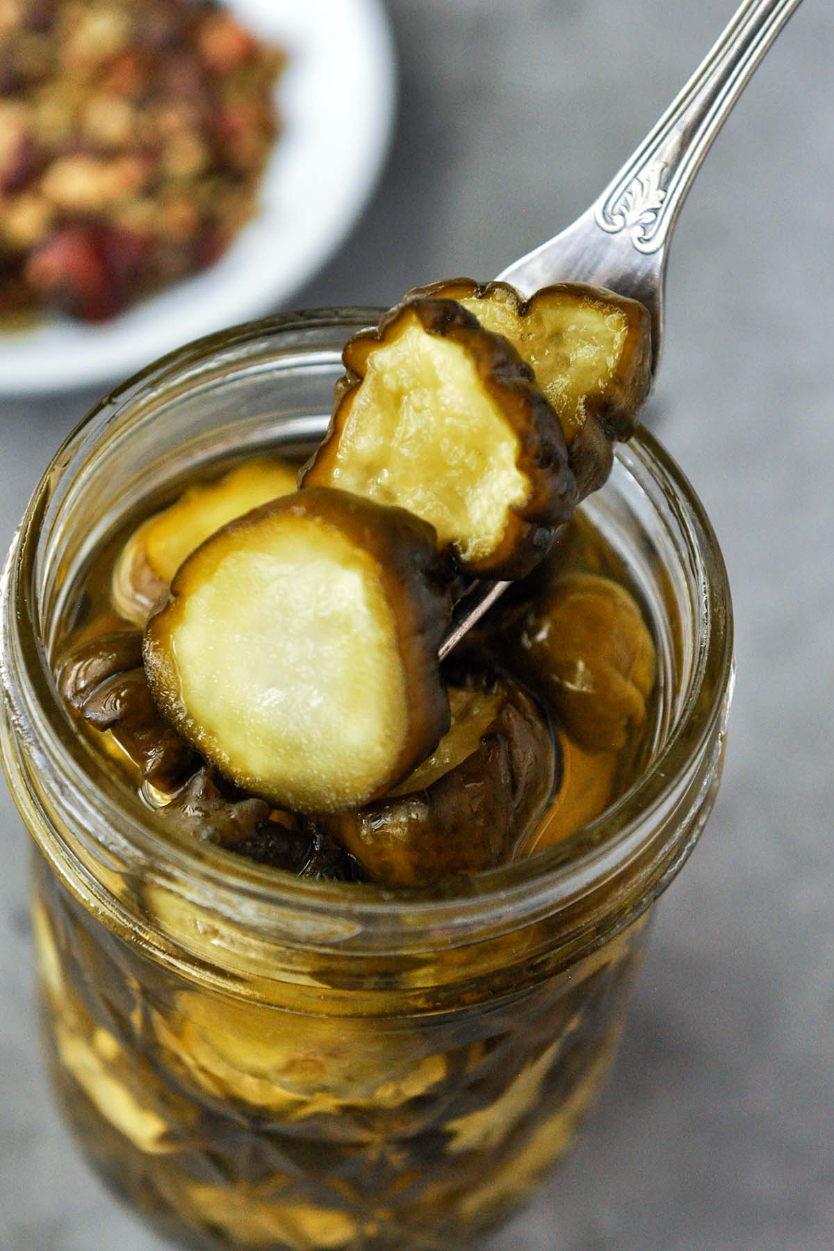 A forkful of candied pickles above the jar.