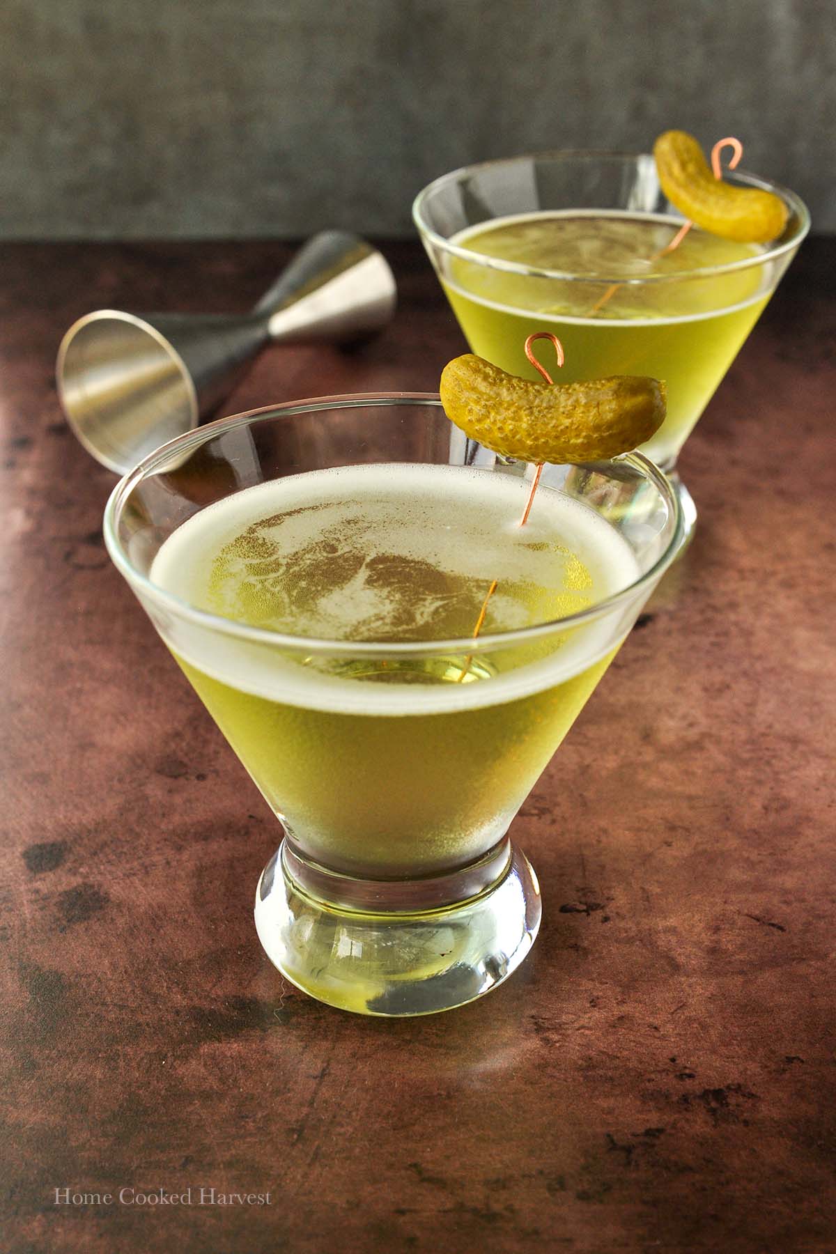 Two glasses of pickle juice martinis with a pickle garnish.
