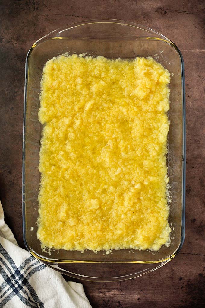 Step one to make dump cake, add pineapple to baking dish.