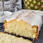 Pineapple pound cake that has been sliced with a pineapple and striped towel in the background.