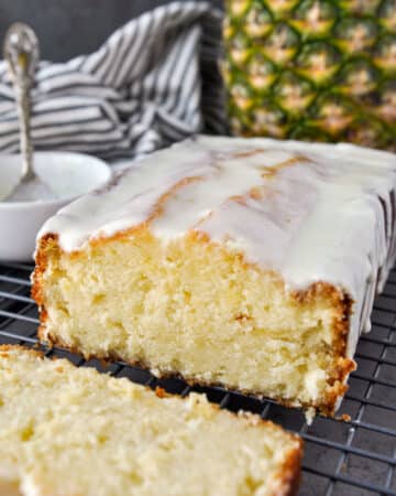 Pineapple pound cake that has been sliced with a pineapple and striped towel in the background.