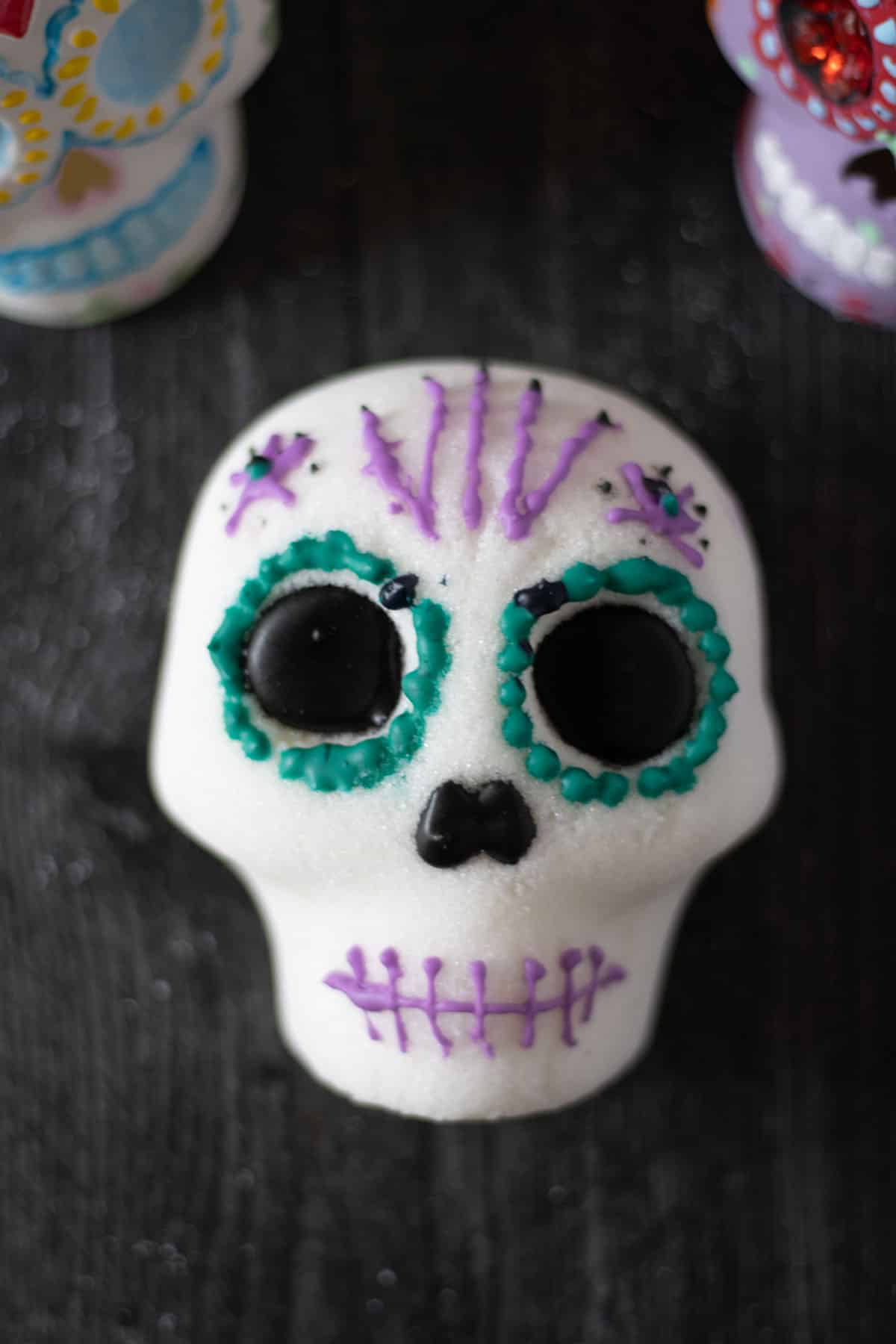 An above view of a decorated sugar skull and two skulls in the background.