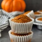 Pumpkin muffins lined up on cooling rack with a pumpkin in the background.