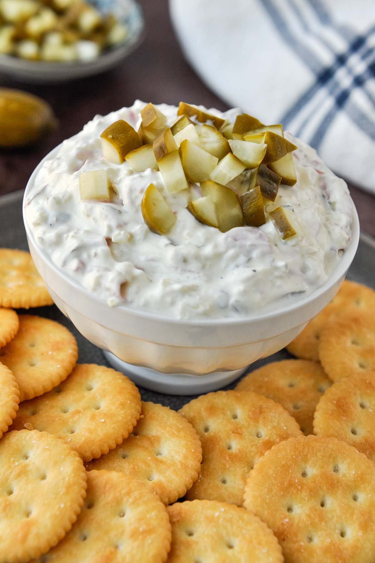 A bowl of pickle wrap dip on a tray of crackers.