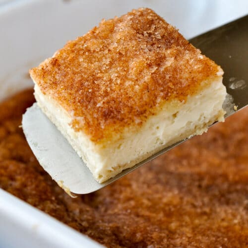A bar on a spatula above a pan of cream cheese bars.