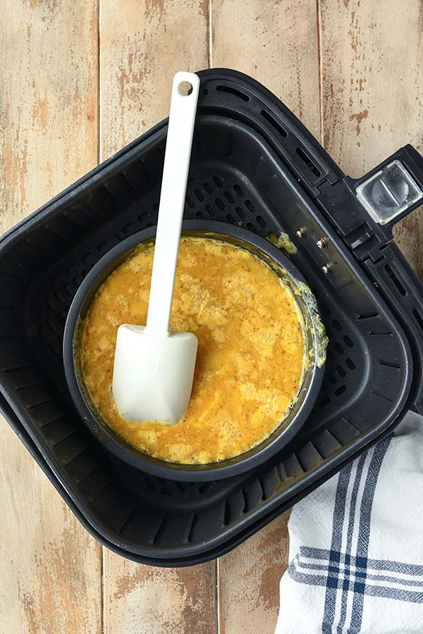 The pan of eggs gets mixed in the air fryer after cooking for a bit. Continue cooking.