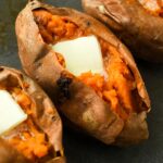 Above view of three cooked sweet potatoes topped with butter.